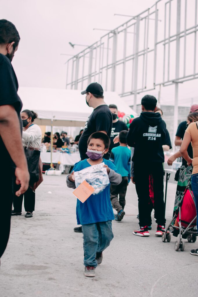 boy holding a bag of donated goods walking through a crowd. Eligible nonprofits can receive $10,000 in Google ads
